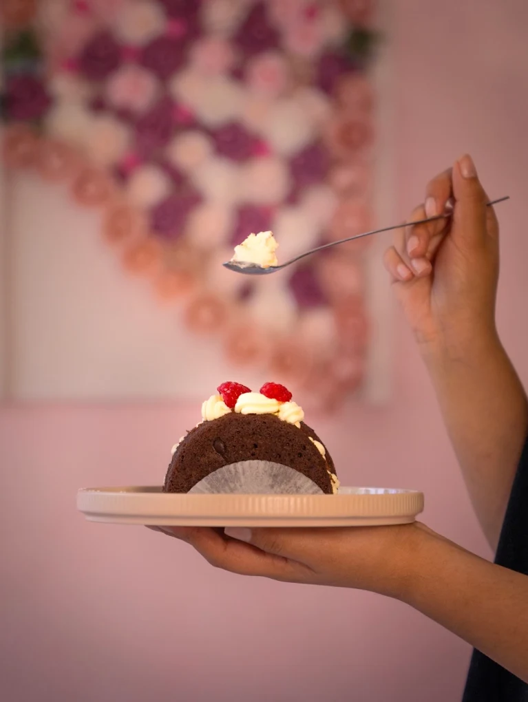 Schokoladendessert mit Sahne und Himbeeren wird vor der Rosenwand serviert